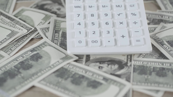 selective focus of calculator and scattered dollar banknotes on table - Séquence, vidéo