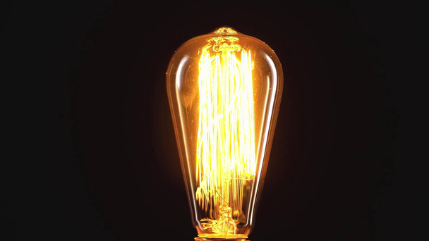incandescent light bulb switching on isolated on black with copy space - Footage, Video
