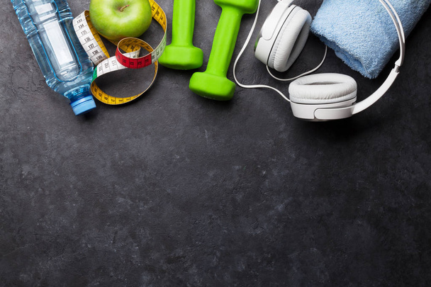 Η ιδέα της γυμναστικής. Κουτά, ακουστικά και μήλο σε πέτρινο φόντο. Κορυφαία προβολή με χώρο για το κείμενό σας - Φωτογραφία, εικόνα