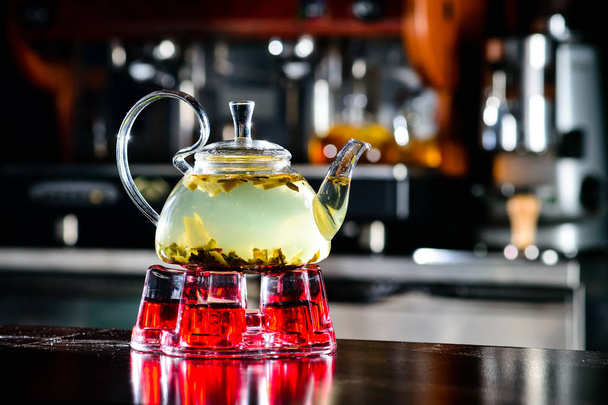 glass teapot with green tea in a cafe, a place for the logo - Foto, afbeelding
