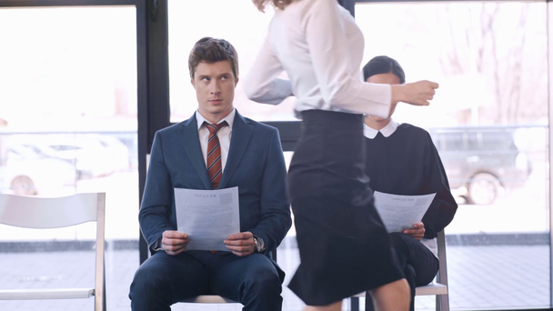 guapo hombre sosteniendo curriculum vitae cerca de la mujer en gafas mirando reloj mientras que la mujer de negocios corriendo en la oficina
  - Metraje, vídeo