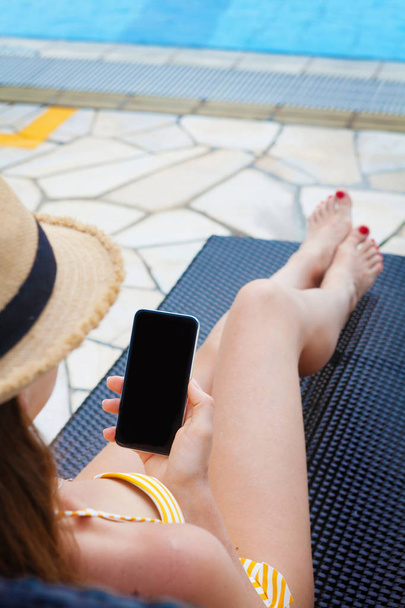 Young woman using smartphone near swimming pool - Foto, immagini