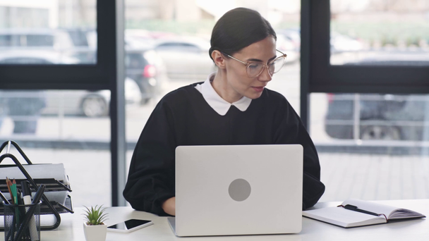 vonzó üzletasszony nézi laptop, mosolygott és írásban notebook modern irodai  - Felvétel, videó