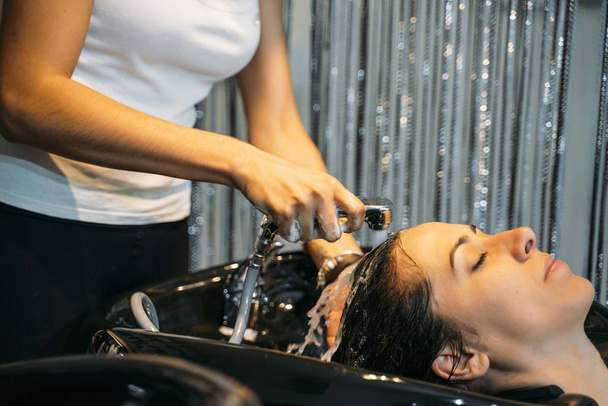 Афро-стиліст миття волосся привабливої леді біля раковини в перукарні
 - Фото, зображення