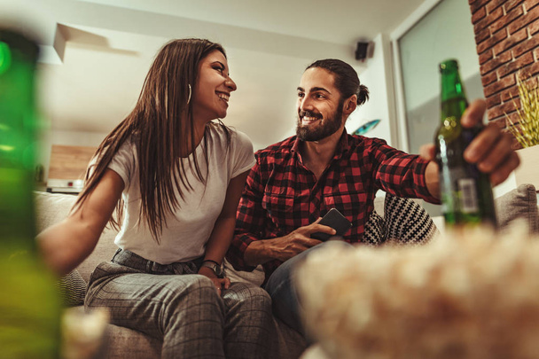 Excited couple playing video games and drinking beer at home on sofa - Foto, immagini
