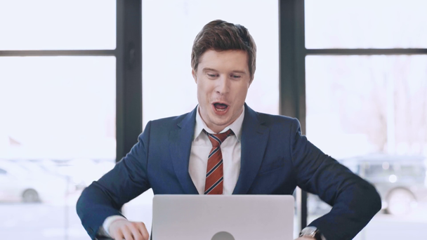 bel homme d'affaires regardant ordinateur portable, souriant et célébrant triomphe dans le bureau moderne
  - Séquence, vidéo
