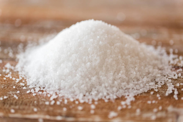 close up of white salt heap on wooden table - Foto, imagen
