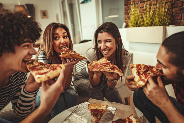 Eğleniyor ve pizza evde yemek neşeli arkadaş grubu - Fotoğraf, Görsel