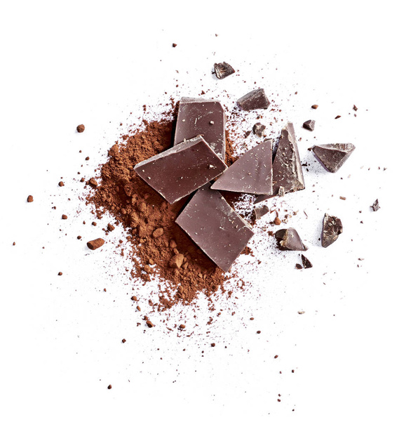 Kakaopulver und Stücke dunkler Schokolade, isoliert auf weißem Hintergrund. Kuchenzutaten, Draufsicht oder Hochwinkelaufnahme. - Foto, Bild