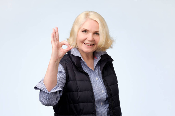 Улыбающаяся старшая блондинка жестом знак ОК
 - Фото, изображение