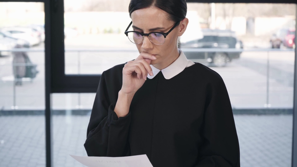 attractive worried woman in glasses pointing with finger while reading resume and learning then smiling before job interview   - Footage, Video