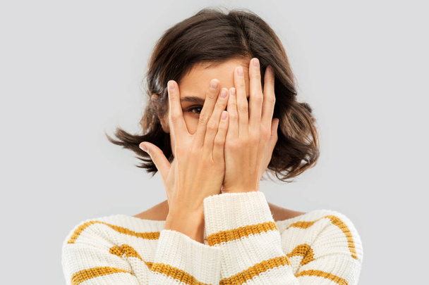 young woman looking by one eye through her fingers - Photo, image