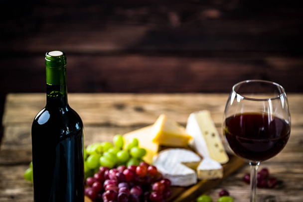 Appetizing cheese with grapes and wine on wooden background - Photo, image