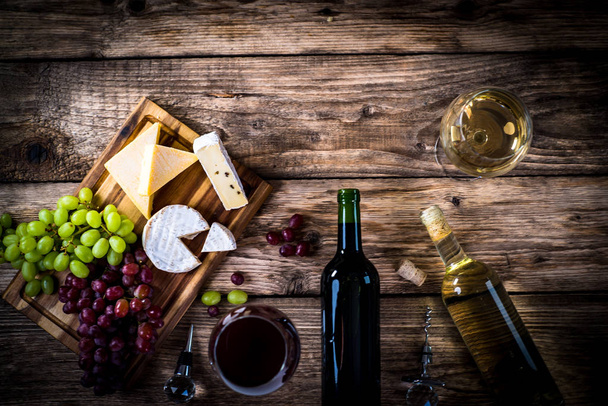 Appetizing cheese with grapes and wine on wooden background - Фото, зображення