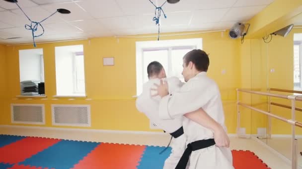 Atletik erkekler aikido dövüş sanatı meşgul. Bir adam rakibini yakalar ve onu üzerine atar - Video, Çekim