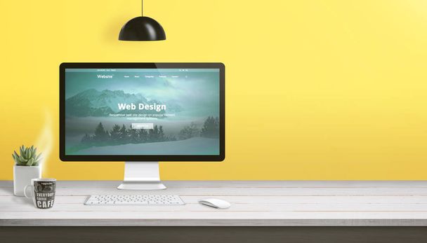 コンピュータディスプレイ、キーボード、マウス、植物、コーヒーのカップとウェブデザインスタジオワークデスク。黄色い壁の横のコピースペース. - 写真・画像
