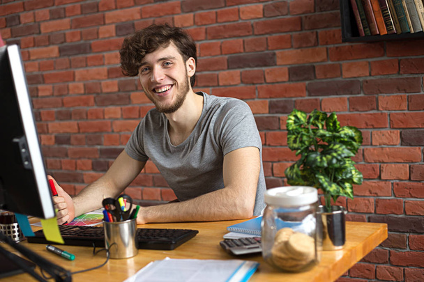 Giovane uomo sorridente che lavora sul suo posto di lavoro
 - Foto, immagini
