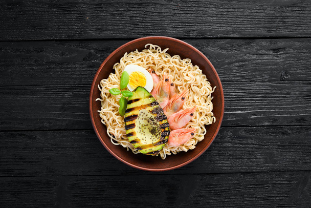 Asian food. Noodles with shrimps, avocados, eggs and chia seeds. On a wooden background. Top view. Free copy space. - Foto, afbeelding