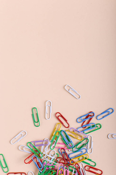 Multicolored paper clips on a coral background, pattern, copy space. - Foto, imagen