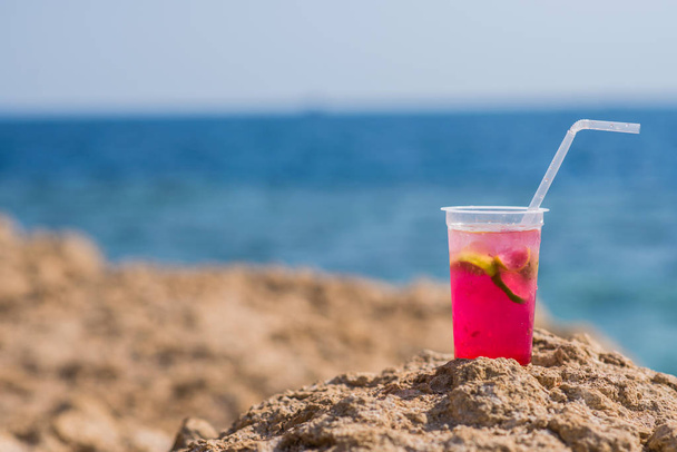 Bright cocktail on a summer beach against the blue sea - Фото, изображение