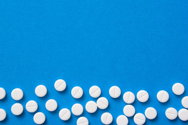White pills on blue background top view for text - Valokuva, kuva