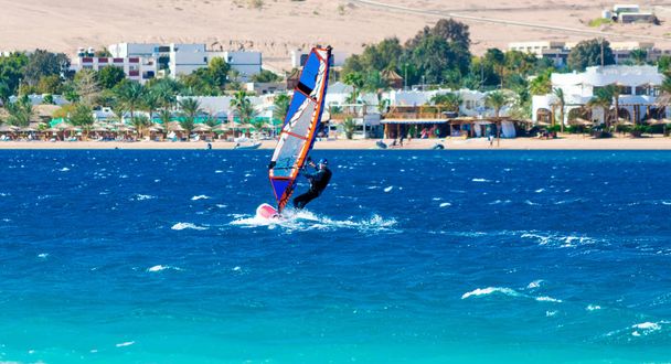 paseos de windsurf en el fondo de la playa con un hotel y
 - Foto, imagen
