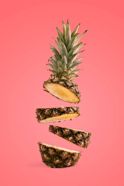 Pineapple sliced, levitates in the air. Concept of summer mood on a liveng coral background. - Φωτογραφία, εικόνα