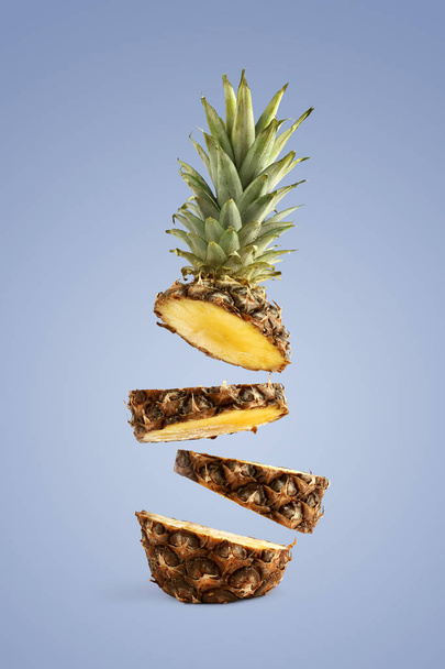 Pineapple sliced, levitates in the air. Concept of summer mood on a blue background. - Photo, image