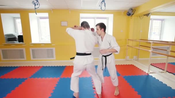 Az aikido harcművészetén tevékenykedő atlétikai férfiak. Egy férfi megragadja az ellenfelét, és dobja őt a padlón - Felvétel, videó
