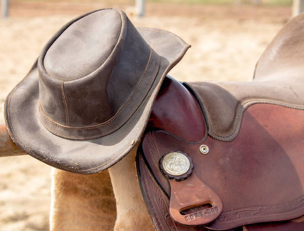 közeli szép retro-stílusú bőr nyereg és lovas bőr kalap, ország stílusban - Fotó, kép