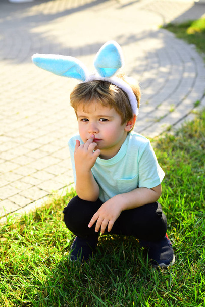 Child like a bunny on green grass outdoors. Easter boy concept. - Foto, afbeelding