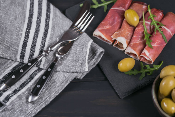 Black stone platter with slices of cured ham or Spanish jamon se - Foto, Bild