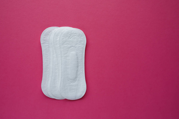 Feminine hygiene pad on a pink background. Concept of feminine hygiene during menstruation. Flat lay, top view. - Zdjęcie, obraz