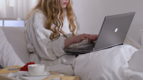 Lady drinking coffee and working on laptop in hotel room during business trip - Πλάνα, βίντεο