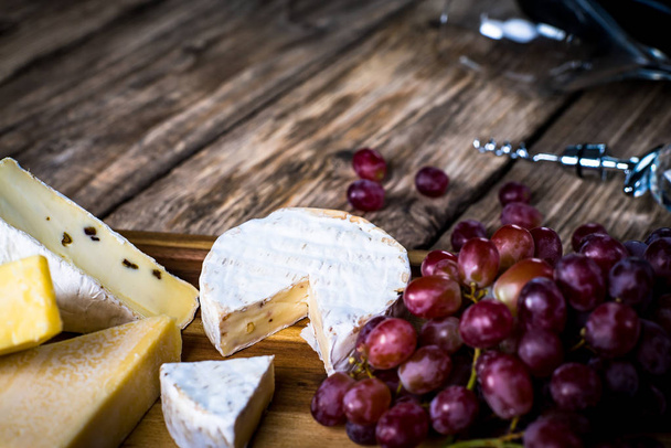 Smakelijke kaas met druiven op houten achtergrond - Foto, afbeelding