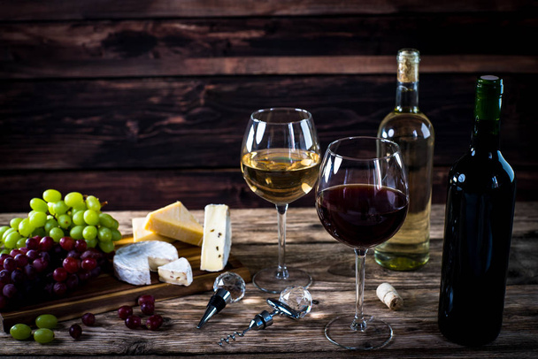 Appetizing cheese with grapes and wine on wooden background - Фото, изображение