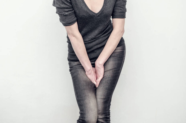 Young slim girl in jeans holds hands pressed between her legs. W - Fotografie, Obrázek