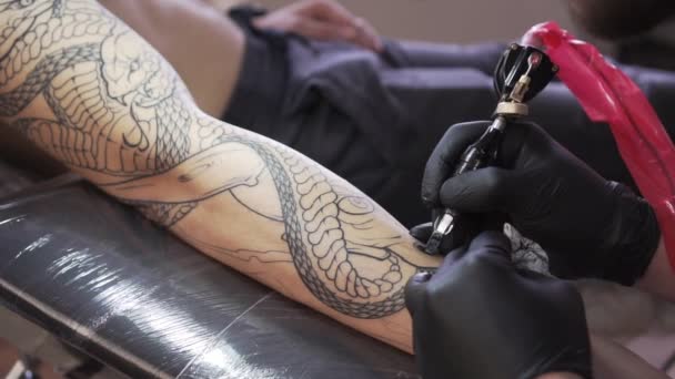 Ένας άντρας κάνει ένα τατουάζ στο χέρι του με μαύρο μελάνι.. - Πλάνα, βίντεο