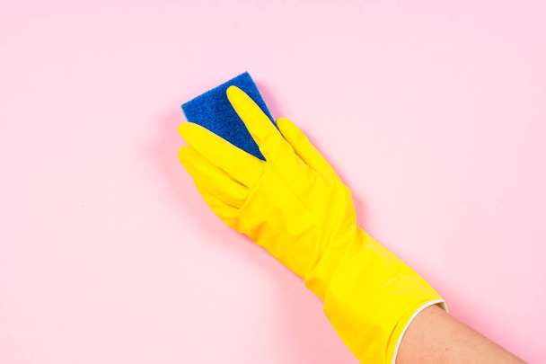 Ręka w żółte rękawiczki i szmata z mikrofibry do czyszczenia różowe tło. - Zdjęcie, obraz