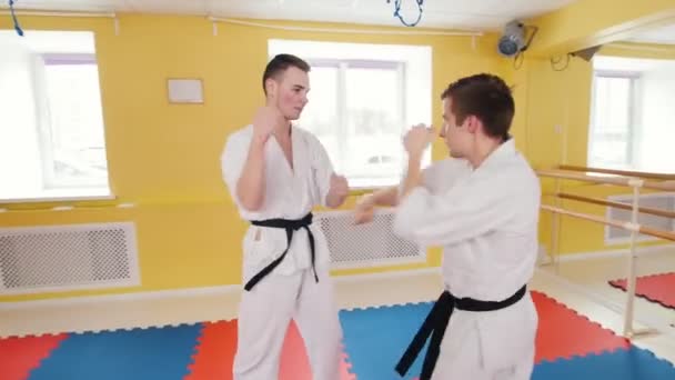 Dwóch mężczyzn trenują swoje umiejętności aikido w studiu. Trenują swoje walki - Materiał filmowy, wideo