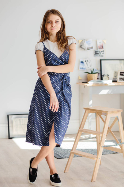 Fashionable woman in a blue sundress with polka dots posing in the Studio. - Photo, Image