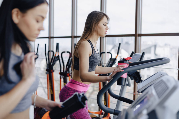 Girls in the gym are trained on treadmills and drink water, smiling - Foto, Imagem