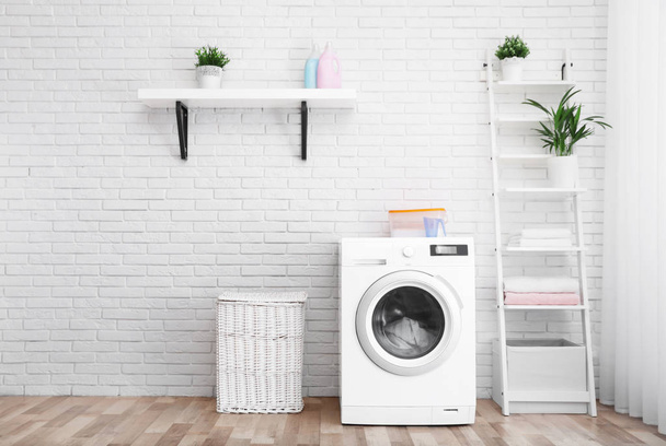 Modern washing machine near brick wall in laundry room interior, space for text - Фото, изображение