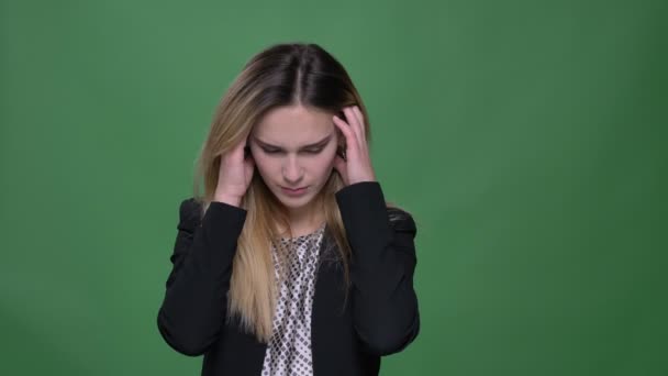 Closeup shoot of young attractive hipster caucasian female having a headache and being exhausted with background isolated on green - Felvétel, videó