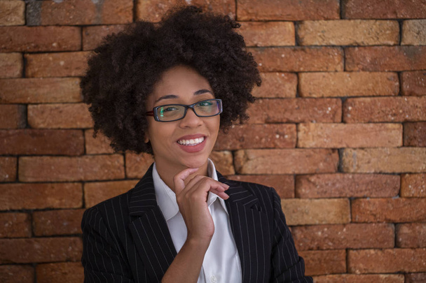 Beautiful African business woman wearing glasses in brick wall background. - Photo, image