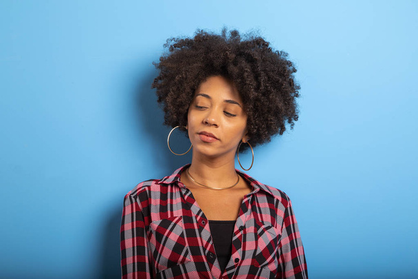 Porträt einer coolen jungen schwarzen Frau, die vor blauer Wand lacht  - Foto, Bild