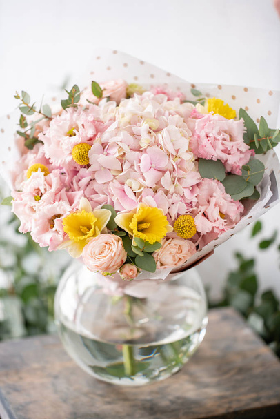 schöner frisch geschnittener Strauß gemischter Blumen in der Vase auf einem Holztisch. die Arbeit des Blumenhändlers in einem Blumenladen. zarte Pastelltöne Farbe - Foto, Bild
