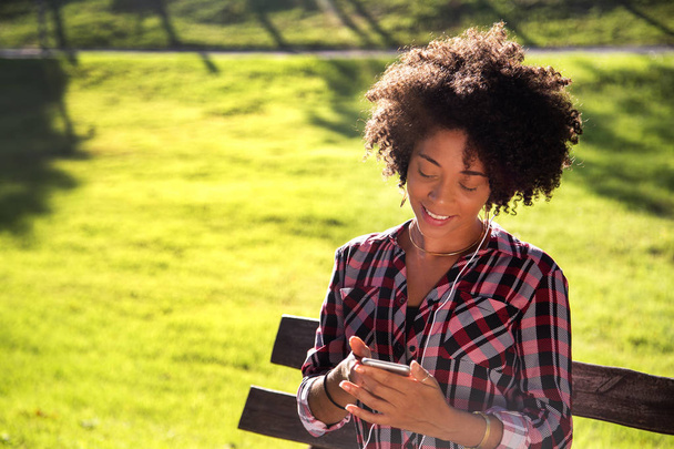 Porträt einer jungen afrikanisch-amerikanischen Frau, die Musik auf dem Handy hört - ImageCollect. - Foto, Bild