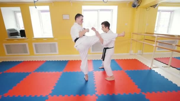 Dos hombres entrenando sus habilidades de aikido en el estudio. Protegiendo de un golpe en la pierna y tirando al oponente al suelo
 - Imágenes, Vídeo