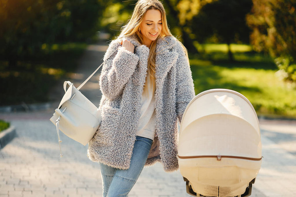 stylish young blonde mother pushing stroller - Fotoğraf, Görsel